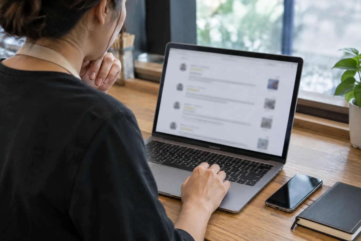 Un professionnel consulte un avis client sur un ordinateur, sans contenu lisible à l’écran.